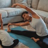cheerful asian mother and daughter stretching body in living room